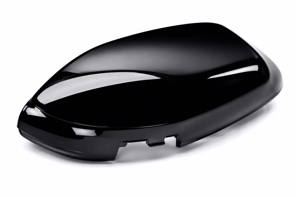 High-gloss black plastic injection molded part reflecting studio lights.